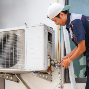 Técnico de aire acondicionado reparando una unidad condensadora.