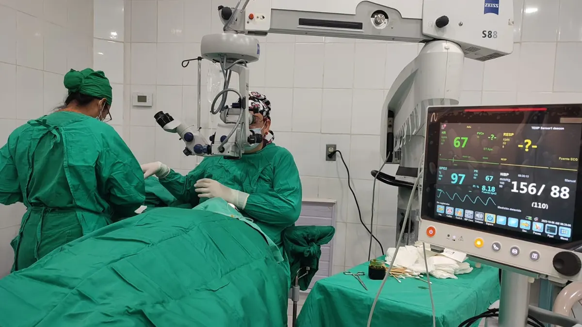 Cirujanos realizando microcirugía utilizando un microscopio quirúrgico y un monitor de constantes vitales del paciente en el Centro Oftalmológico de Ciudad Sandino