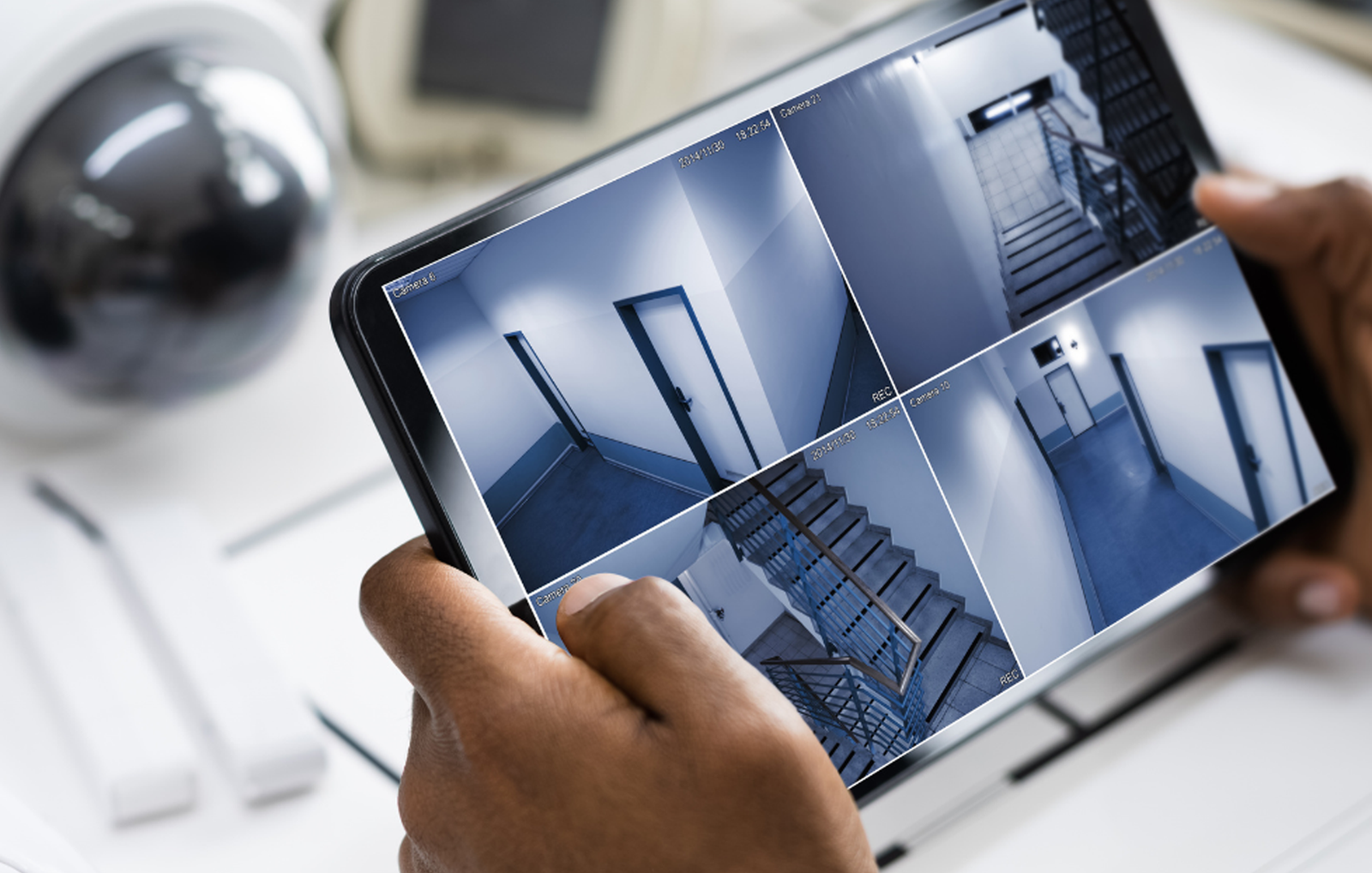 Un profesional de seguridad supervisa las señales de múltiples cámaras de videovigilancia en una tableta digital para la vigilancia del edificio.